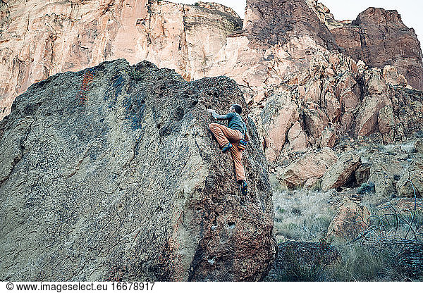 Male climber getting close to the top of the boulder in Smith Rock