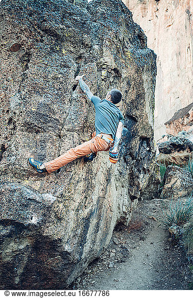 Male climber getting to the top of the boulder in Smith Rock park