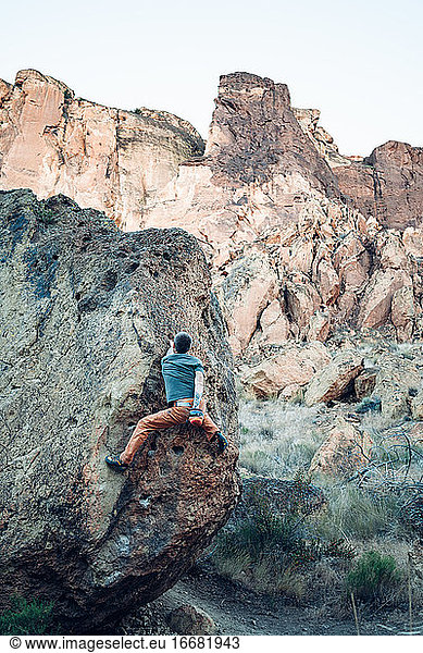 Male climber getting to the top of the boulder in Smith Rock park
