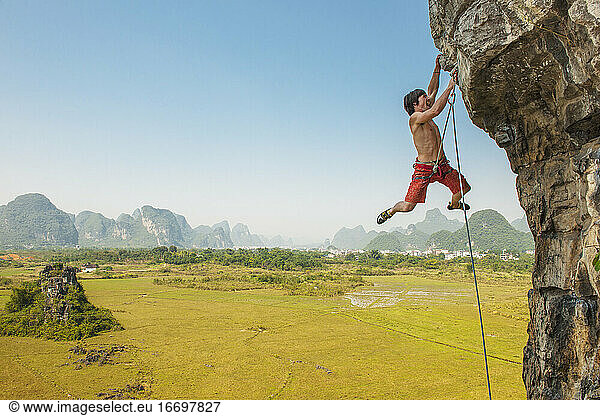 male climber pulling up on overhanging rock in Yangshuo / China
