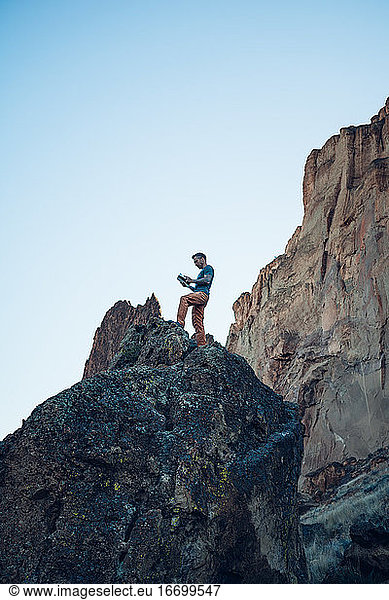 Male climber reading a guide book on the top of the boulder in Oregon