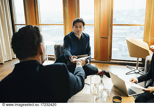 Male colleagues discussing over document in office