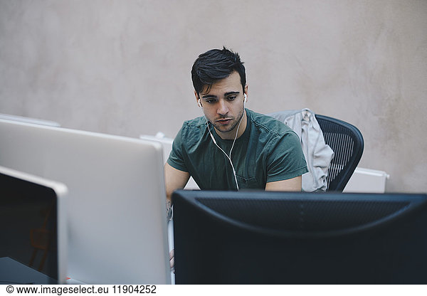 Male computer programmer using desktop PC in office
