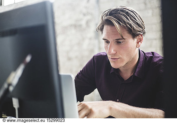 Male computer programmer using laptop while working in office