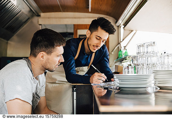 Male coworkers looking at order in food truck