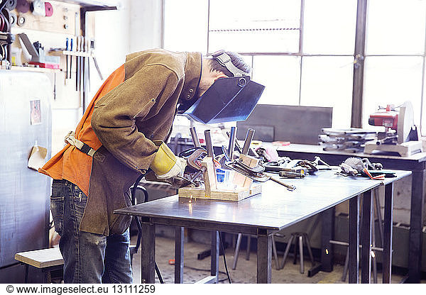 Male craftsperson welding metal at wood shop