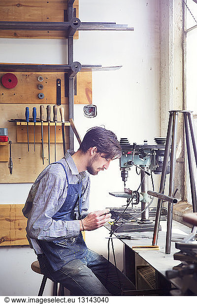 Male craftsperson working on machinery at wood shop