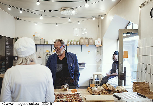 Male customer buying food from owner at bakery
