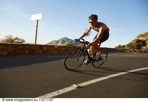 Male cyclist cycling on sunny corner