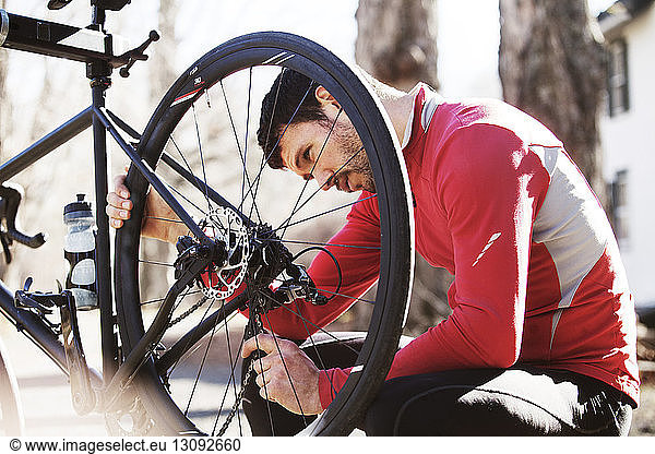 Male cyclist examining bicycle outdoors