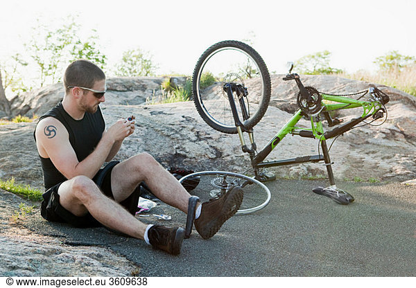 Male cyclist fixing punctured tyre