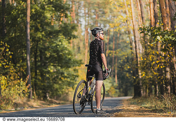 Male cyclist on a gravel bike enjoying the forest view. Millenni