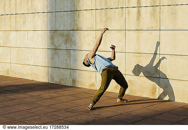 Male dancer bending over backwards while dancing on footpath