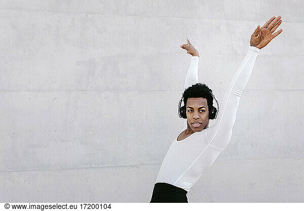 Male dancer looking away while doing urban dance against white wall