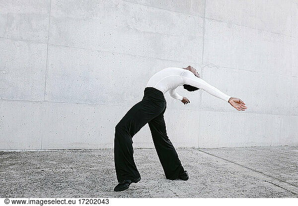 Male dancer practicing urban dance against white wall
