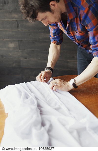Male designer pinning white textile at table