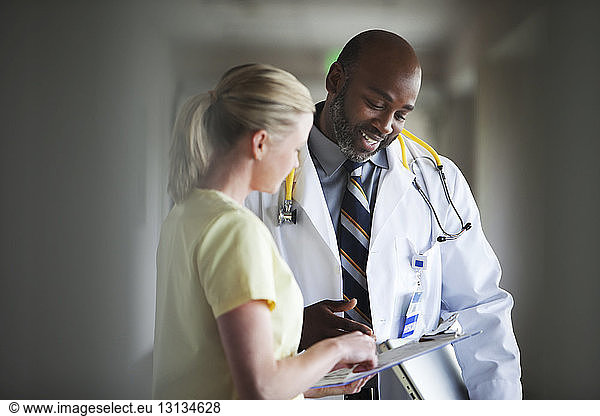 Male doctor checking papers with nurse at hospital