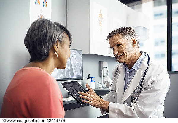 Male doctor explaining x-ray on tablet computer to patient in clinic