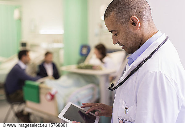 Male doctor using digital tablet  making rounds in hospital ward