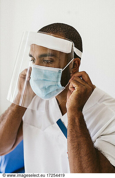 Male doctor wearing protective face mask and face shield during COVID-19