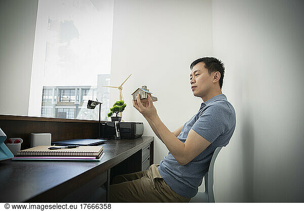 Male engineer looking at house model at office desk