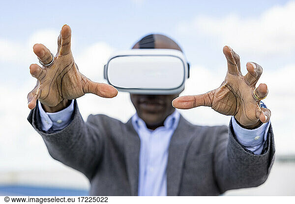 Male entrepreneur gesturing while wearing Virtual reality headset outdoors