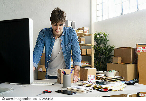 Male entrepreneur looking at cardboard package at desk