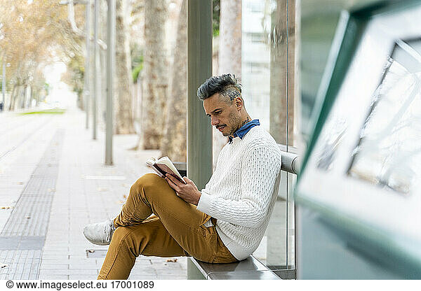 Male entrepreneur reading diary at bus stop