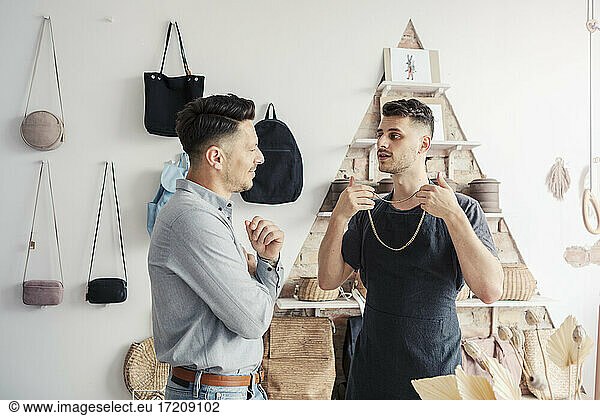 Male entrepreneur showing chain to customer in design studio