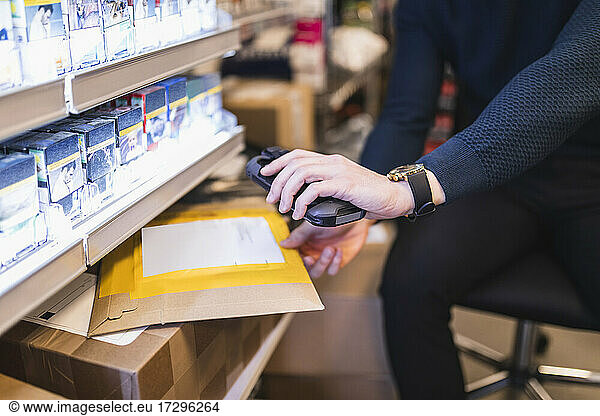 Male entrepreneur using bar code reader while analyzing package in store