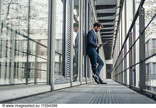 Male entrepreneur using digital tablet while standing at corridor