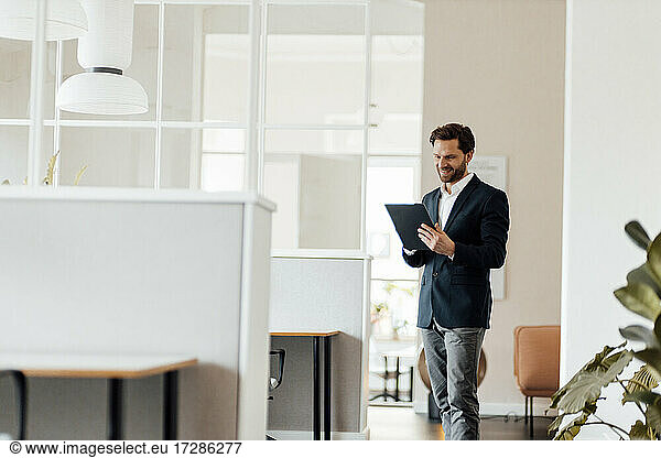 Male entrepreneur using digital tablet while standing at office