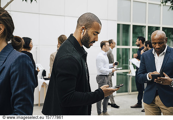 Male entrepreneur using phone while standing outside office