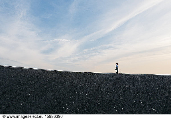 Male entrepreneur walking on hill against sky during sunset