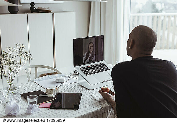 Male entrepreneur with female colleague on video call through laptop during pandemic