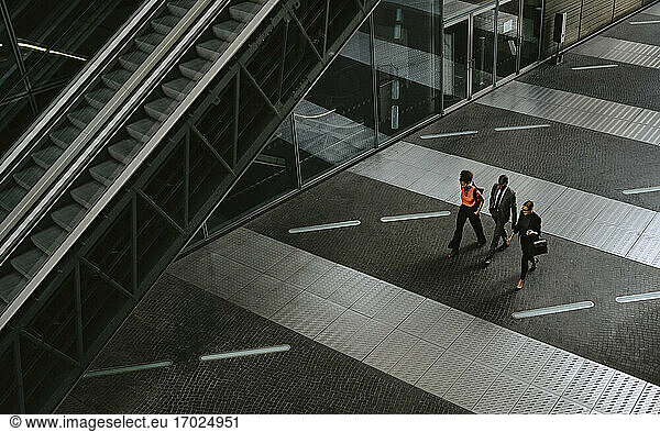Male entrepreneur with female colleagues discussing while walking by escalator