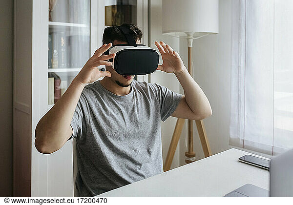 Male entrepreneur with Virtual reality headset while sitting at home office