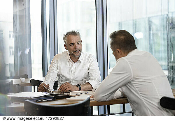 Male entrepreneurs discussing over documents at desk in office