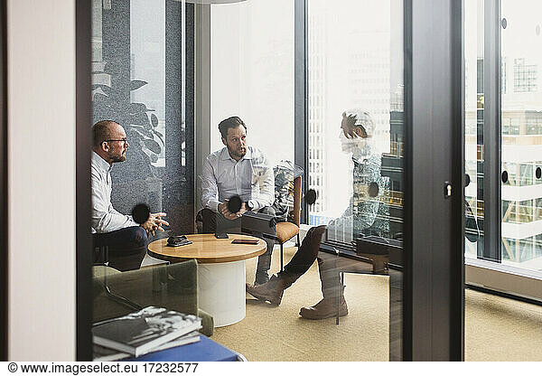 Male entrepreneurs planning strategy during meeting seen through door office