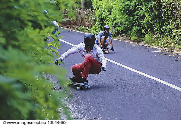 Male friends skateboarding on road
