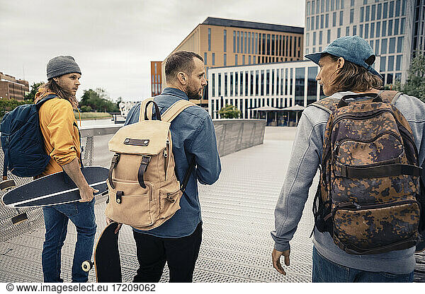Male friends with backpack walking on bridge