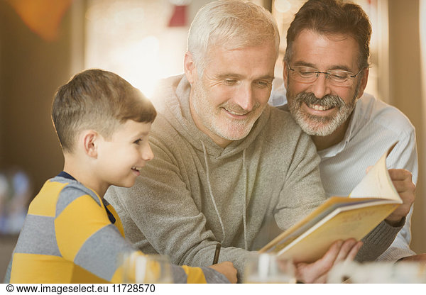Male gay parents reading book to son