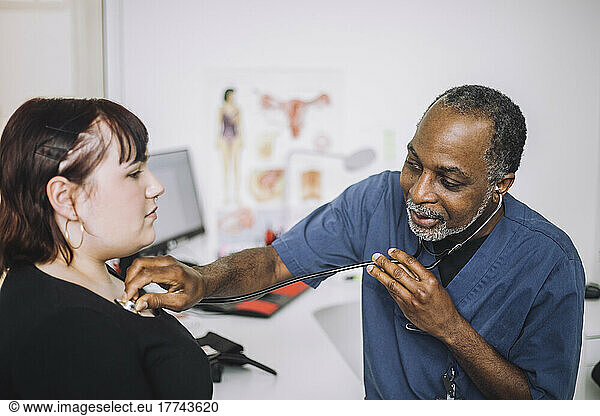 Male healthcare expert with stethoscope examining female patient in clinic