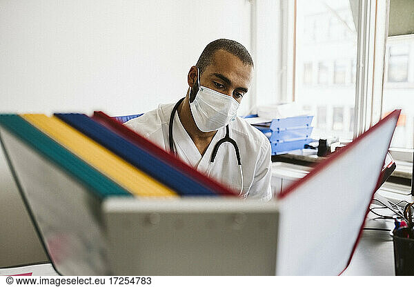 Male healthcare worker reading files at medical clinic during COVID-19