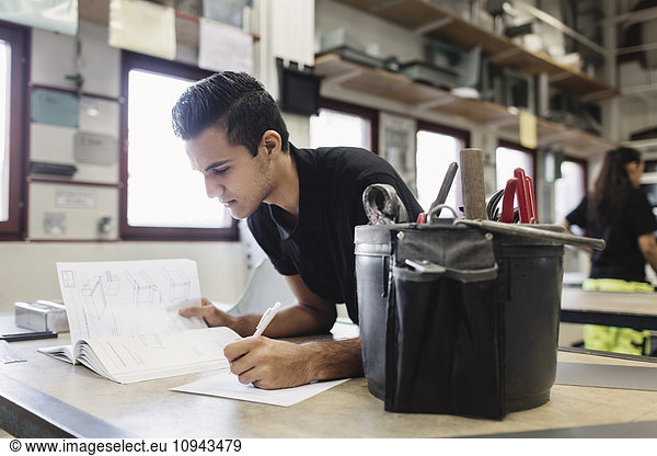 Male high school student taking notes in training class