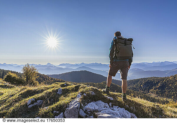 Male hiker admiring Bavarian Prealps at foggy sunrise