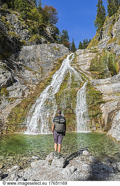 Male hiker admiring Glasbach Waterfall in Bavarian Prealps
