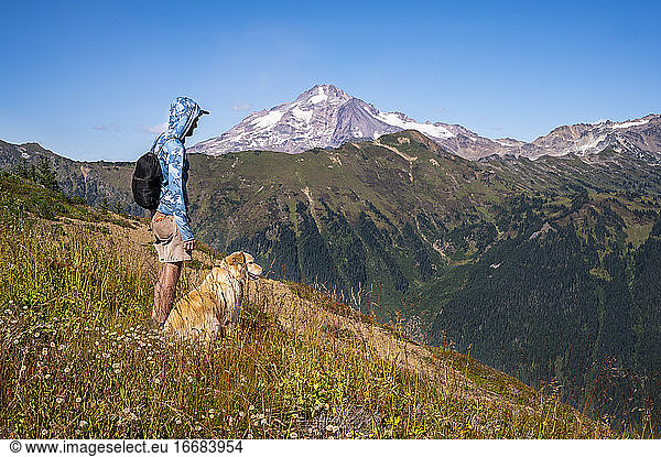 Male hiker and dog with glacier peak in the distance