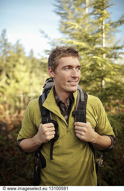 Male hiker looking away while standing in forest