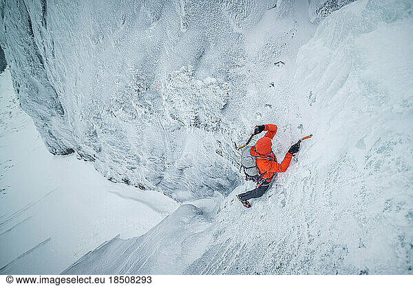 Male ice climber free soloing a pitch of ice in the cold